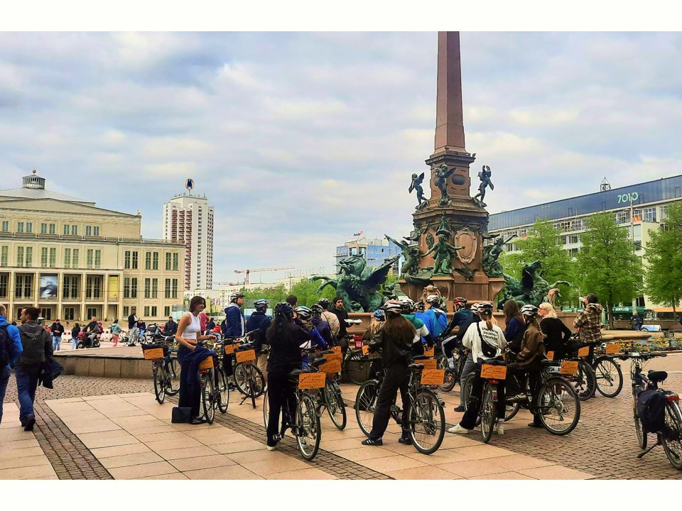 Eine von Leipzig BikeTours geführte Gruppe Fahrradfahrer, vor dem Mendebrunnen in der Innenstadt