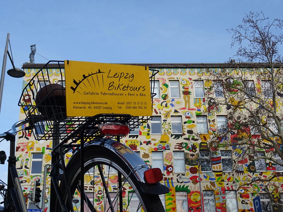 Ein Fahrrad vom Fahrradtour-Anbieter Leipzig Leipzig-Biketours vor einem Haus voller Streetart in Leipzig